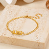 Gold stainless steel zodiac constellation charm bracelet resting on a light beige stone surface.