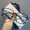 A pair of black retro anti-blue light sunglasses resting on a white paper against a gray background.