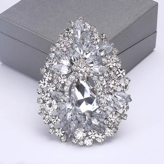 Broche florale en cristal élégante avec un grand diamant central entouré de pierres claires scintillantes.