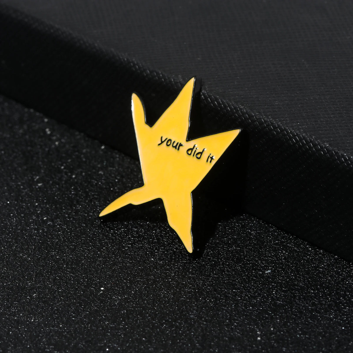 A yellow enamel pin shaped like a lightning bolt with the text your did it on a black surface.