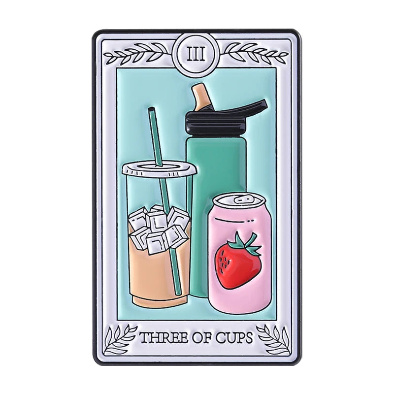 A tarot card enamel pin featuring the Three of Cups, depicting a drink with a straw and a strawberry can.