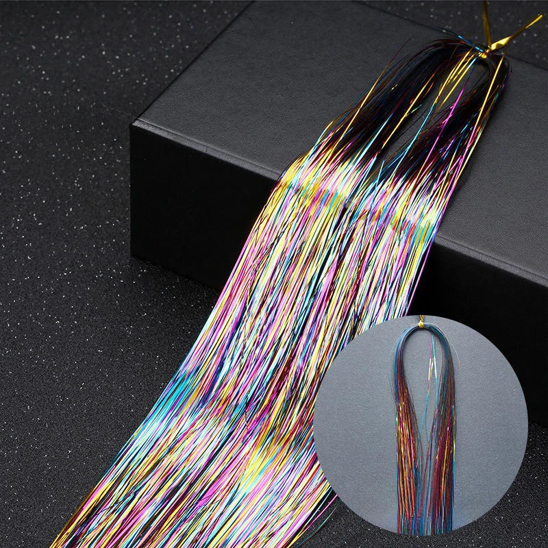 A bundle of rainbow glitter hair extensions strands laid out on a dark surface.
