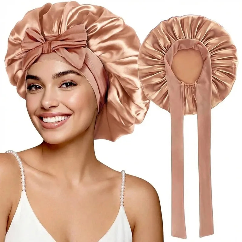 Una mujer modela un gorro de dormir de satén color rosa empolvado con largas cintas.