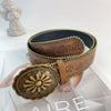 A vintage PU leather boho western belt with a gold sunburst buckle displayed on a white surface.