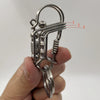 Une main tient un porte-clés mécanique en acier inoxydable avec une chaîne et un mécanisme à ressort.