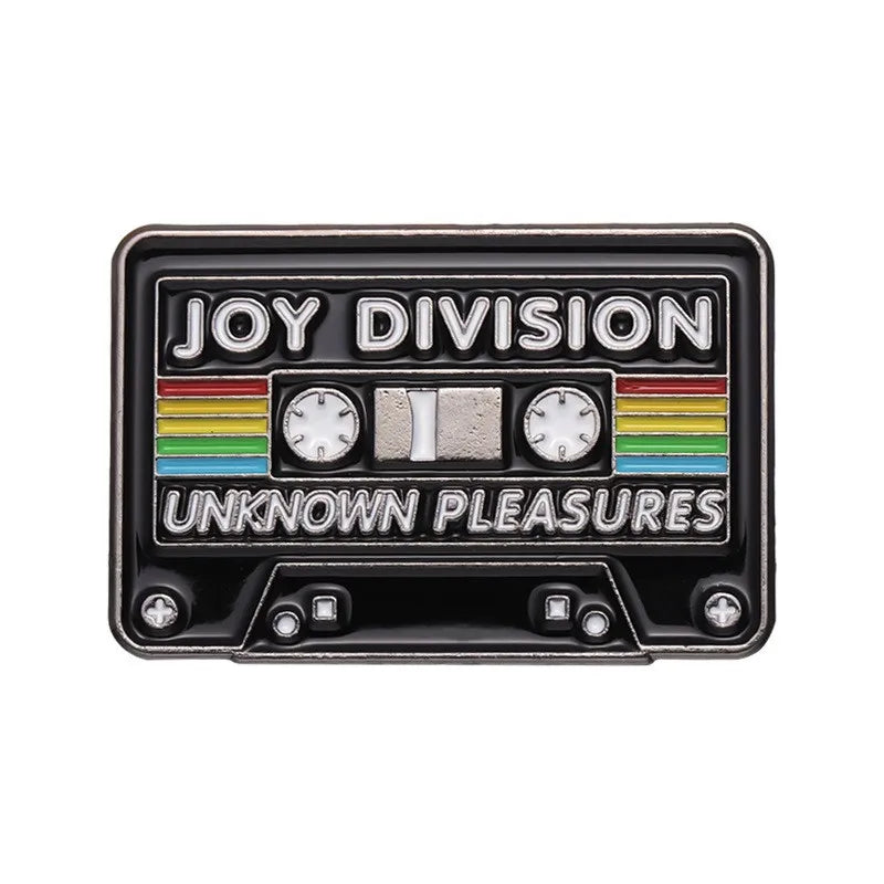 A black enamel pin featuring the text JOY DIVISION and UNKNOWN PLEASURES with colored stripes and circular dials.