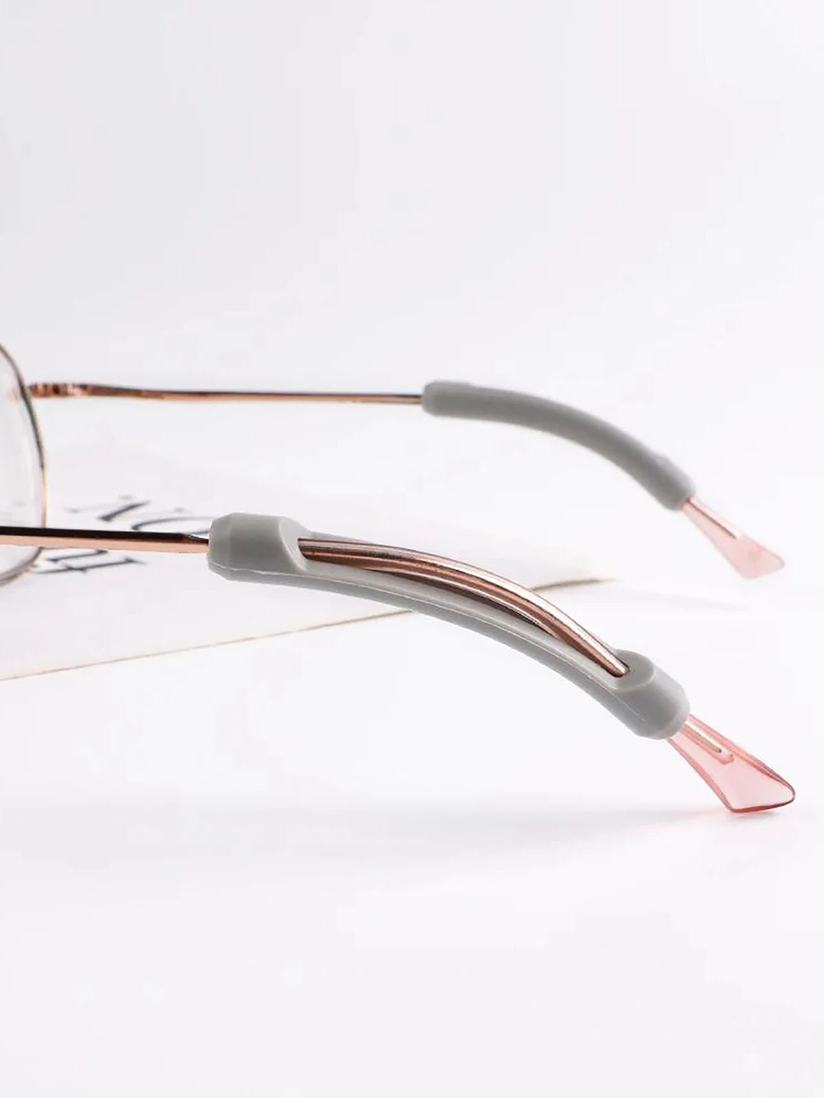 Nahaufnahme eines rosegoldfarbenen rutschfesten Silikon-Eye-Frames für Brillen auf weißem Papier.