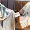 A light pink and white floral print silk scarf draped over a tailored jacket on a brown leather sofa.