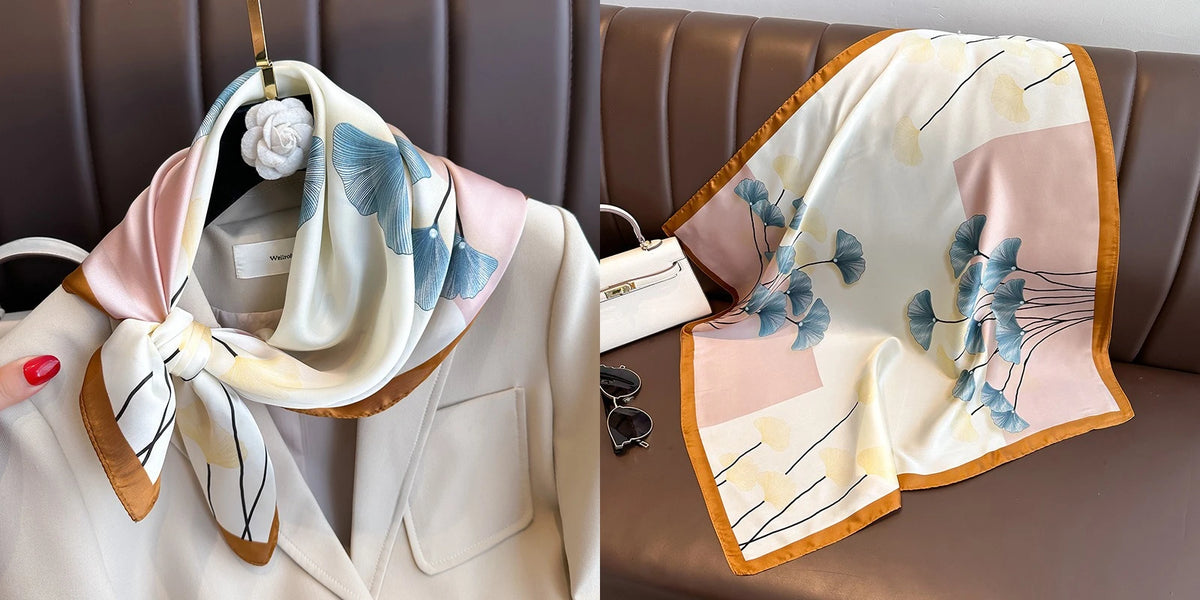 A light pink and white floral print silk scarf draped over a tailored jacket on a brown leather sofa.