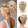 A blonde woman shows off a voluminous, curly updo hairstyle with wispy strands and light highlights.