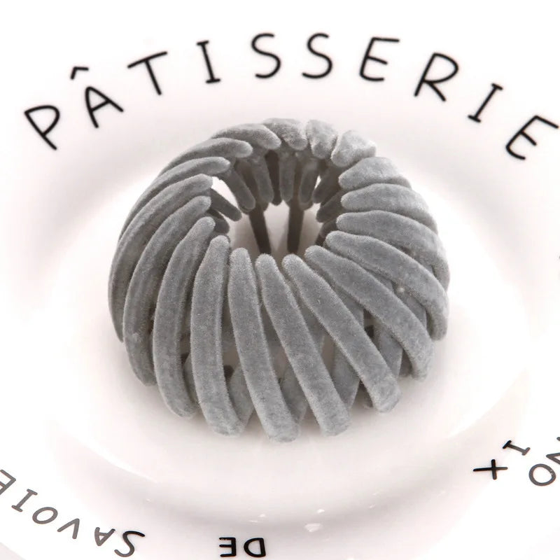 A close-up of elegant gray horsetail hair clips arranged in a circular pattern on a white background.