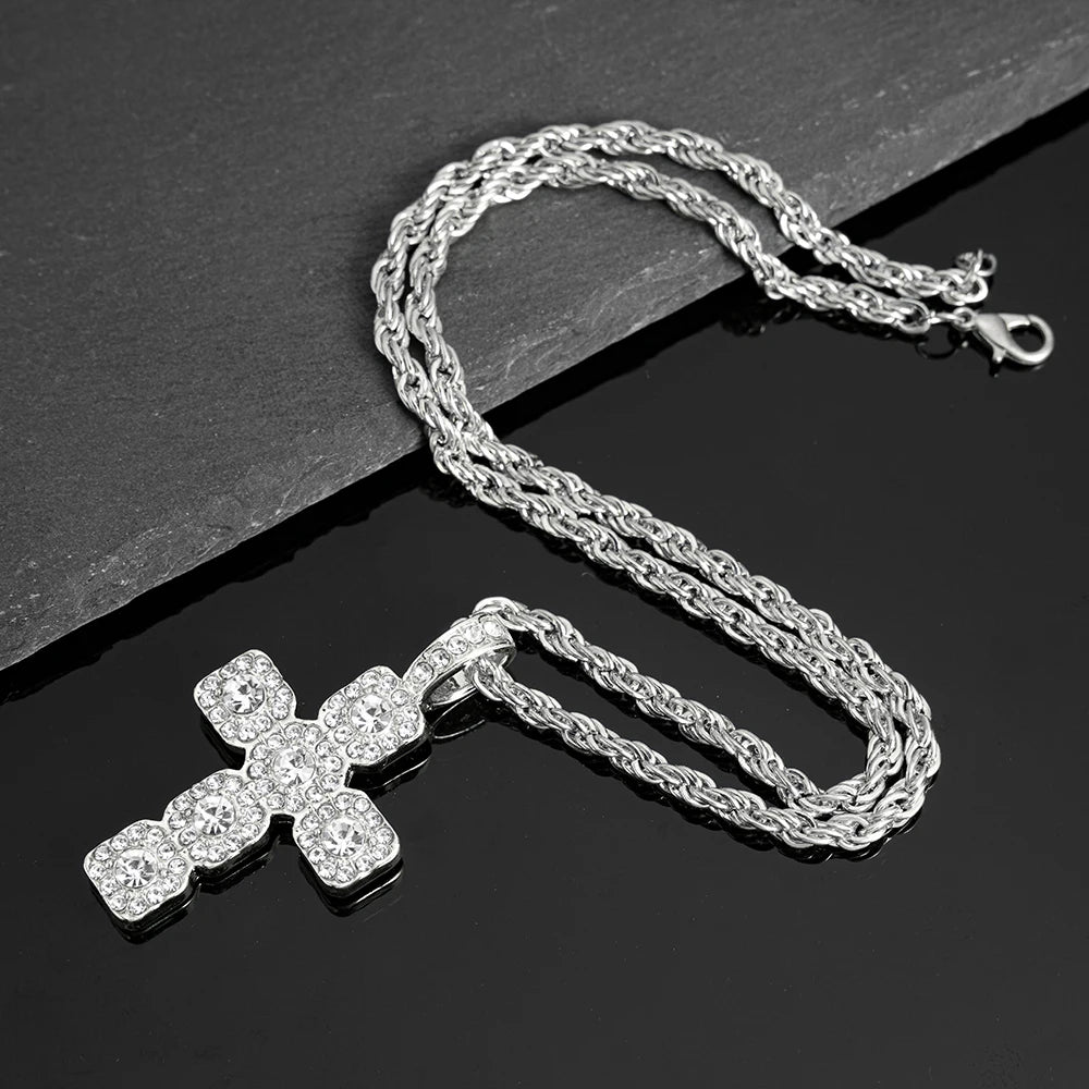 Silver rhinestone cross pendant necklace laid on a dark surface.