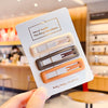 A set of vintage frosted geometry hair clips in various neutral tones, held by a hand.