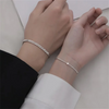 A pair of dainty stainless steel heart link bracelets worn on a person's wrist.