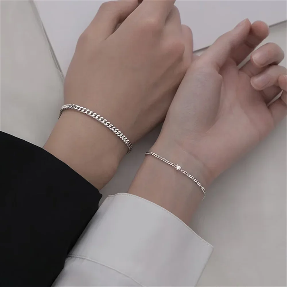 A pair of dainty stainless steel heart link bracelets worn on a person's wrist.