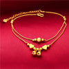 Gold-plated heart bell anklets for women displayed on a red fabric background
