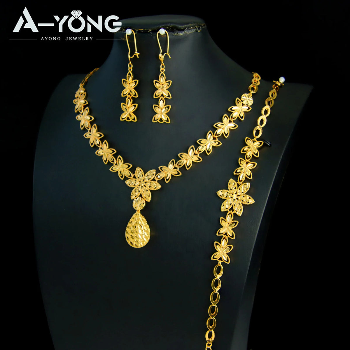 A set of luxury gold plated bridal jewelry featuring earrings and a necklace displayed on a black mannequin.