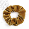 A close-up of a set of six golden brown velvet scrunchies for hair ties.