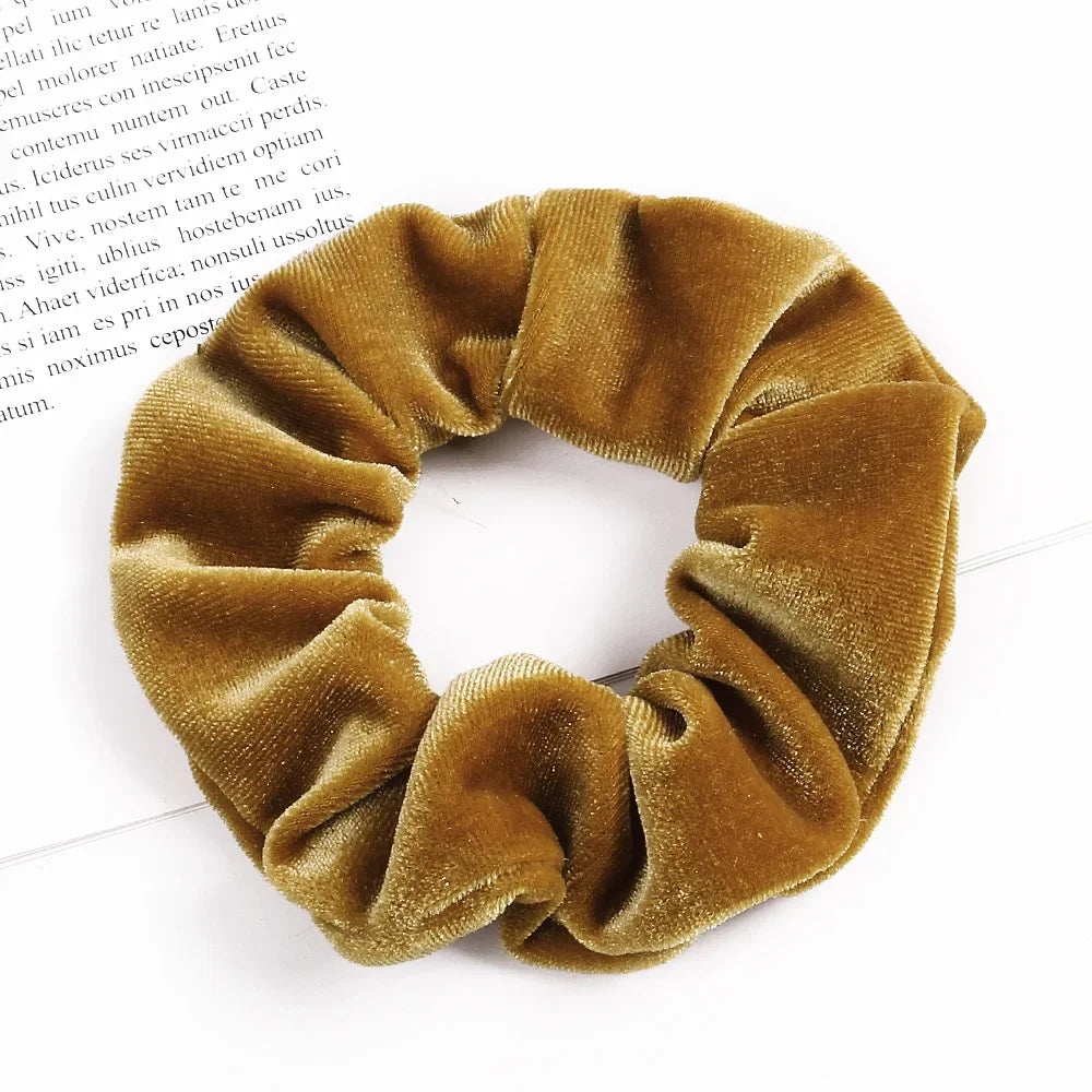 A close-up of a set of six golden brown velvet scrunchies for hair ties.
