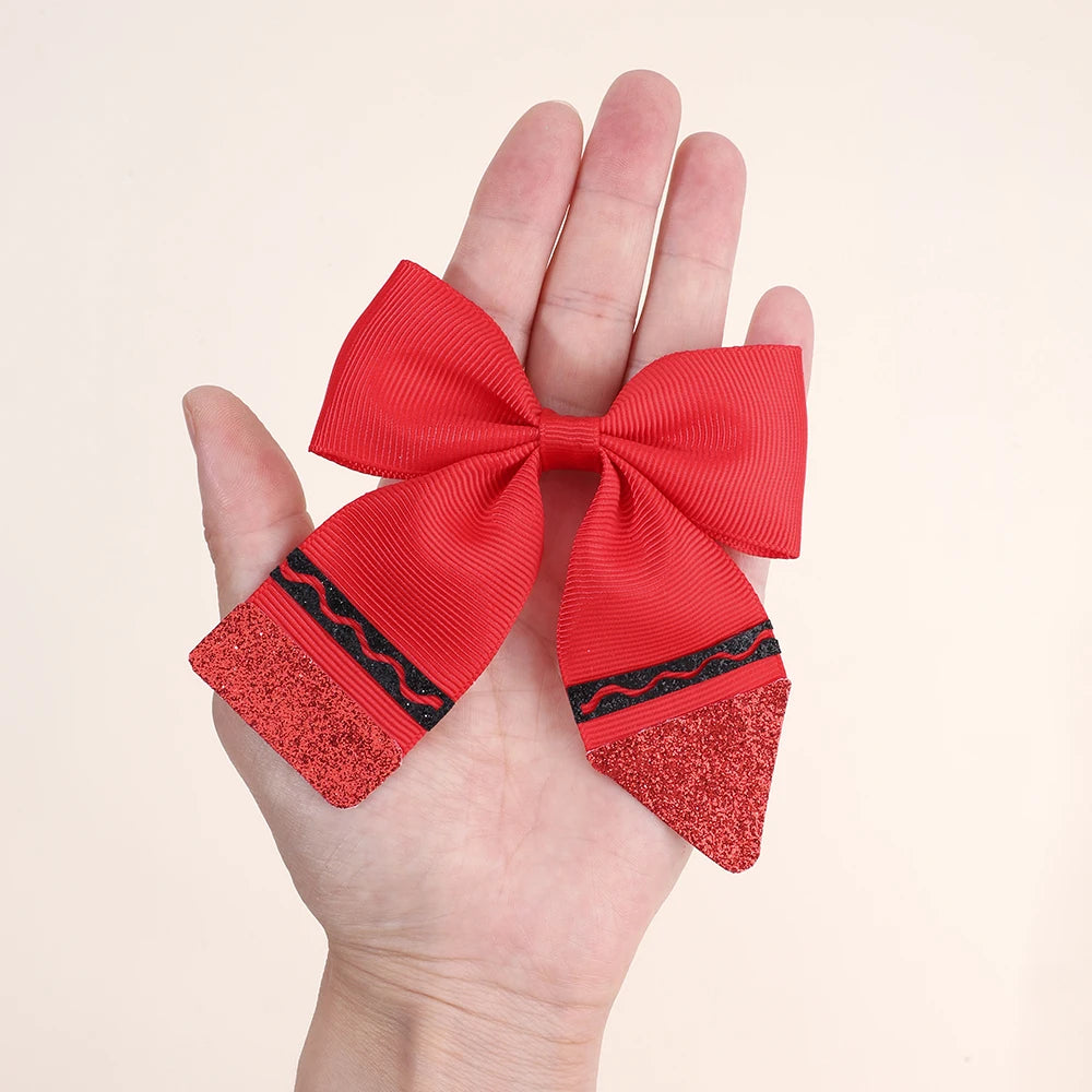 A hand holds a red bow hair clip set featuring glitter and black trim.