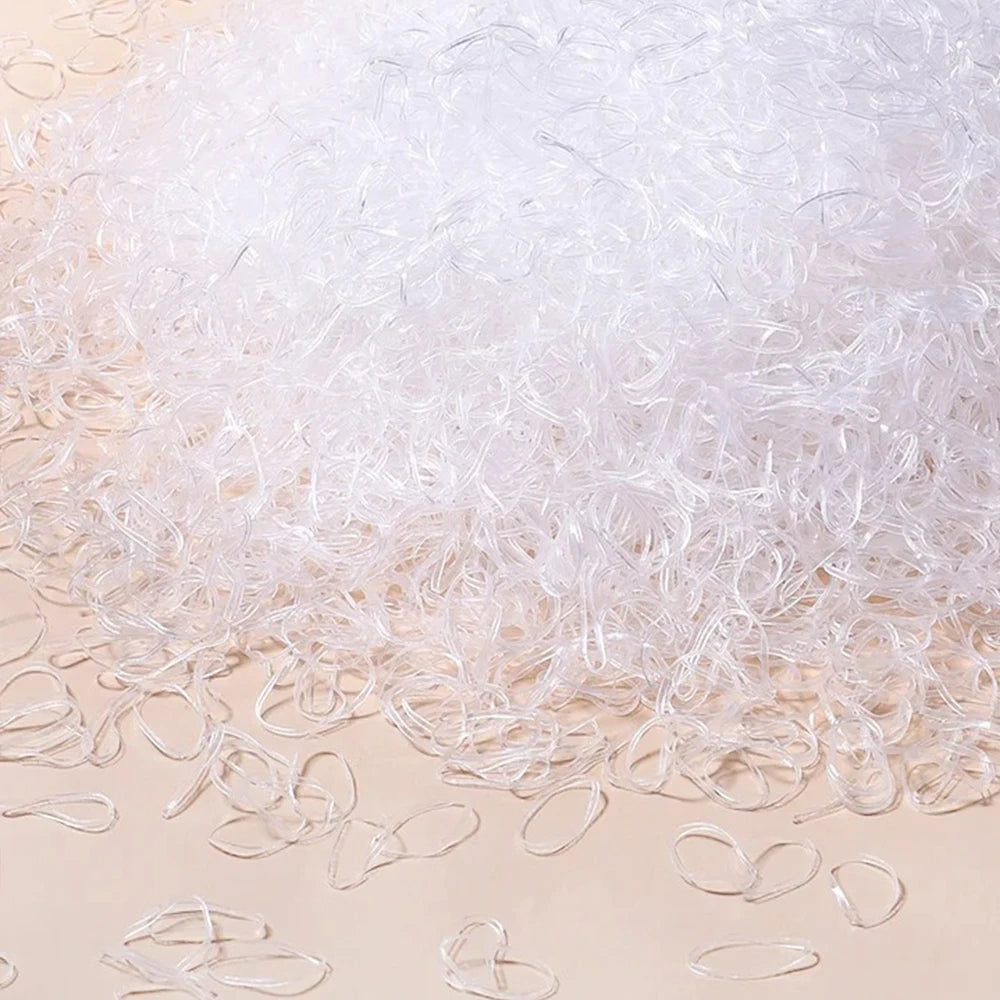 A pile of clear disposable rubber hair ties scattered on a light surface.