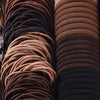 Une pile d'accessoires pour cheveux élastiques pour femmes dans diverses nuances de brun et de noir.