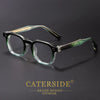 A pair of black retro square anti-blue light eyewear with green accents resting on a dark surface.