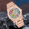 A close-up of a rose gold retro luminous quartz wristwatch resting on a dark, textured surface.