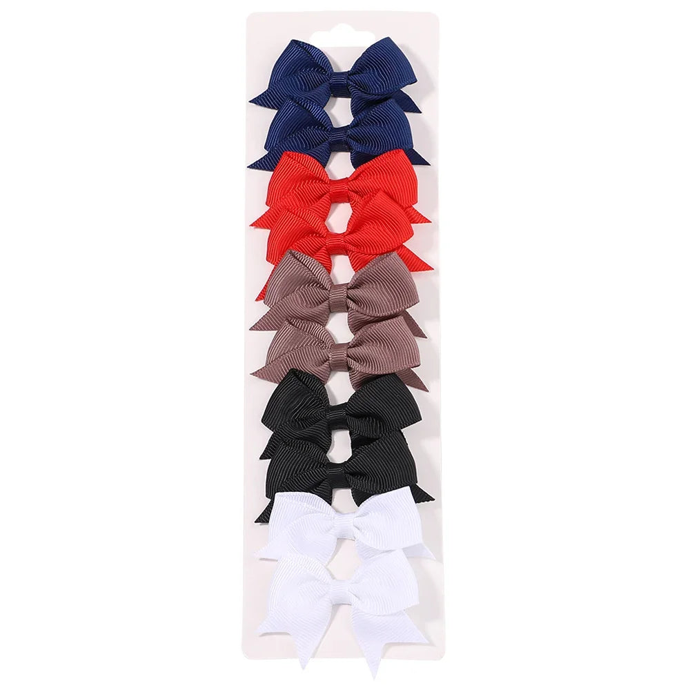 A collection of nine handmade ribbon bow hair clips in various colors including blue, red, brown, and black.
