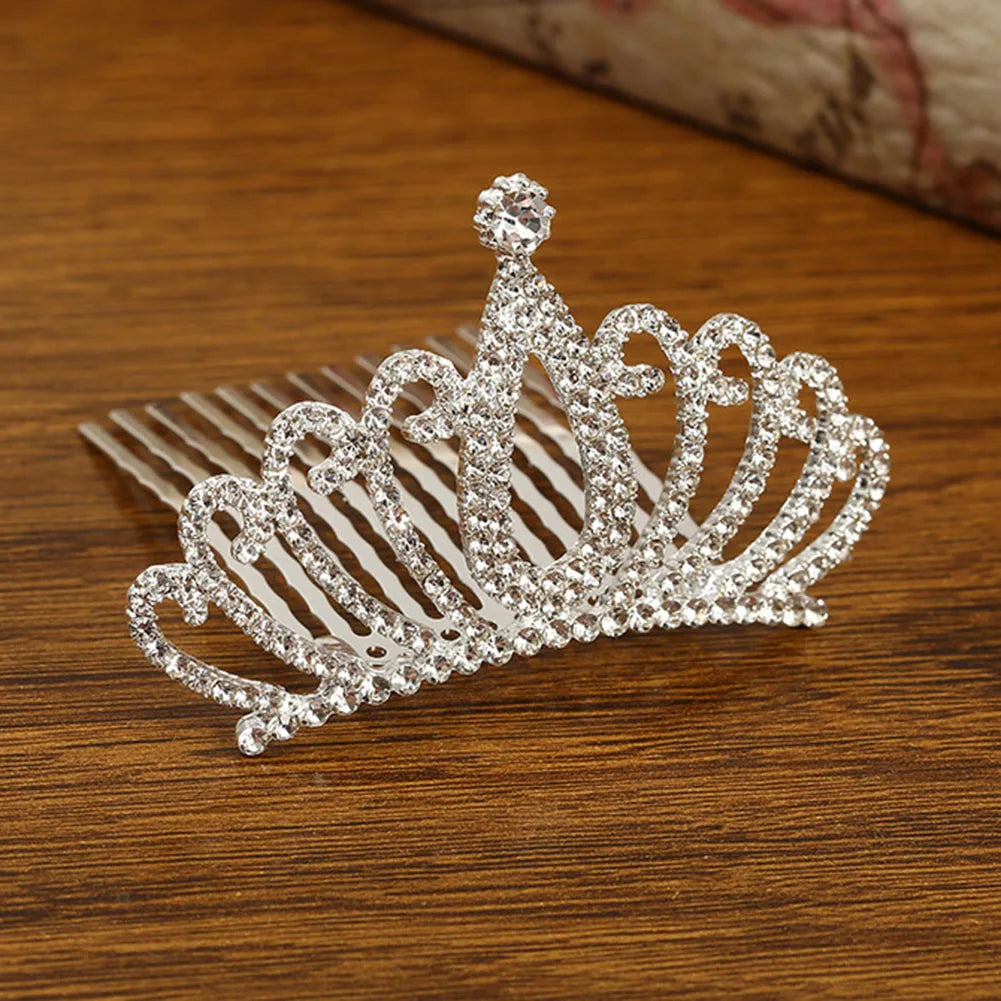 A sparkling crystal princess tiara hair comb for women resting on a wooden surface.