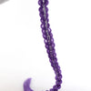 A purple braided hair ponytail with silver tinsel extensions is being held by a hand.