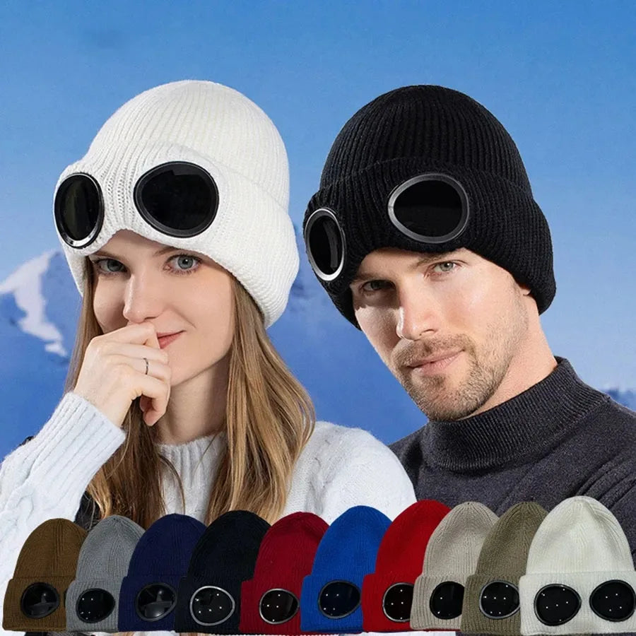 A woman and a man model a white knit windproof hat and a black knit hat against a blue sky background.