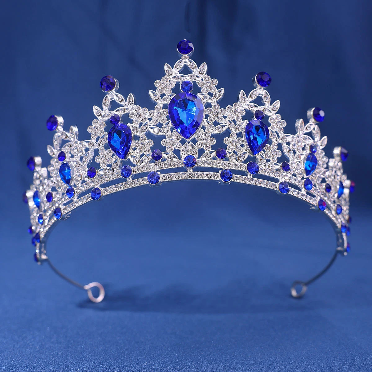 A sparkling crystal rhinestone tiara and headband set featuring blue gemstones against a blue background.