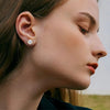Close-up of a woman wearing simulated diamond stud earrings on her ear.