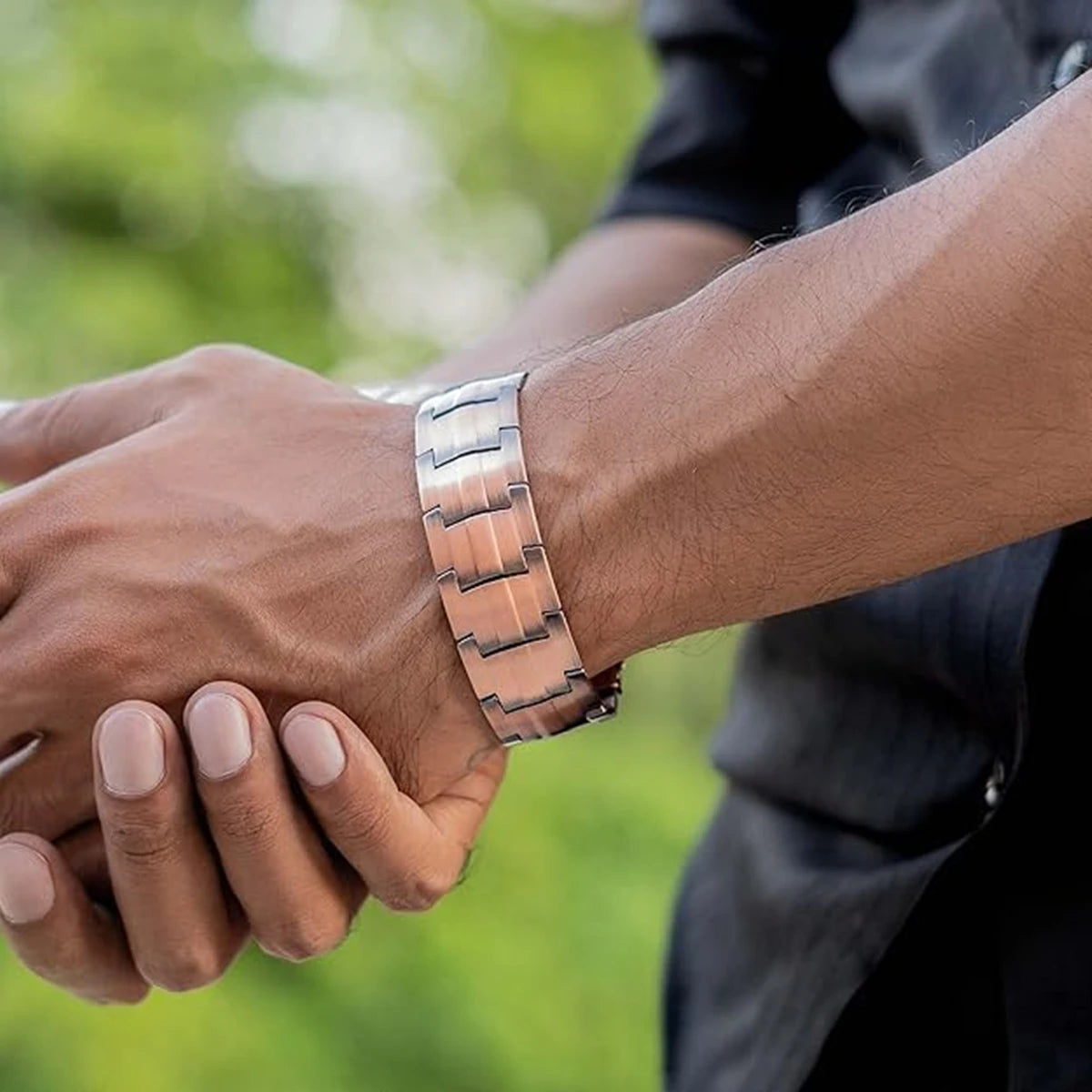 A person's hand is wearing a pure copper magnetic bracelet on their wrist.