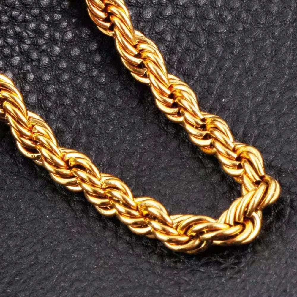 A close-up of a thick, braided 18K gold rope chain necklace lying on a dark surface.