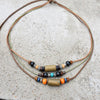 A set of boho vintage wood and stone bead necklaces laid on a gray concrete surface.