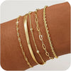 A set of dainty gold plated stackable bracelets worn on a wrist.