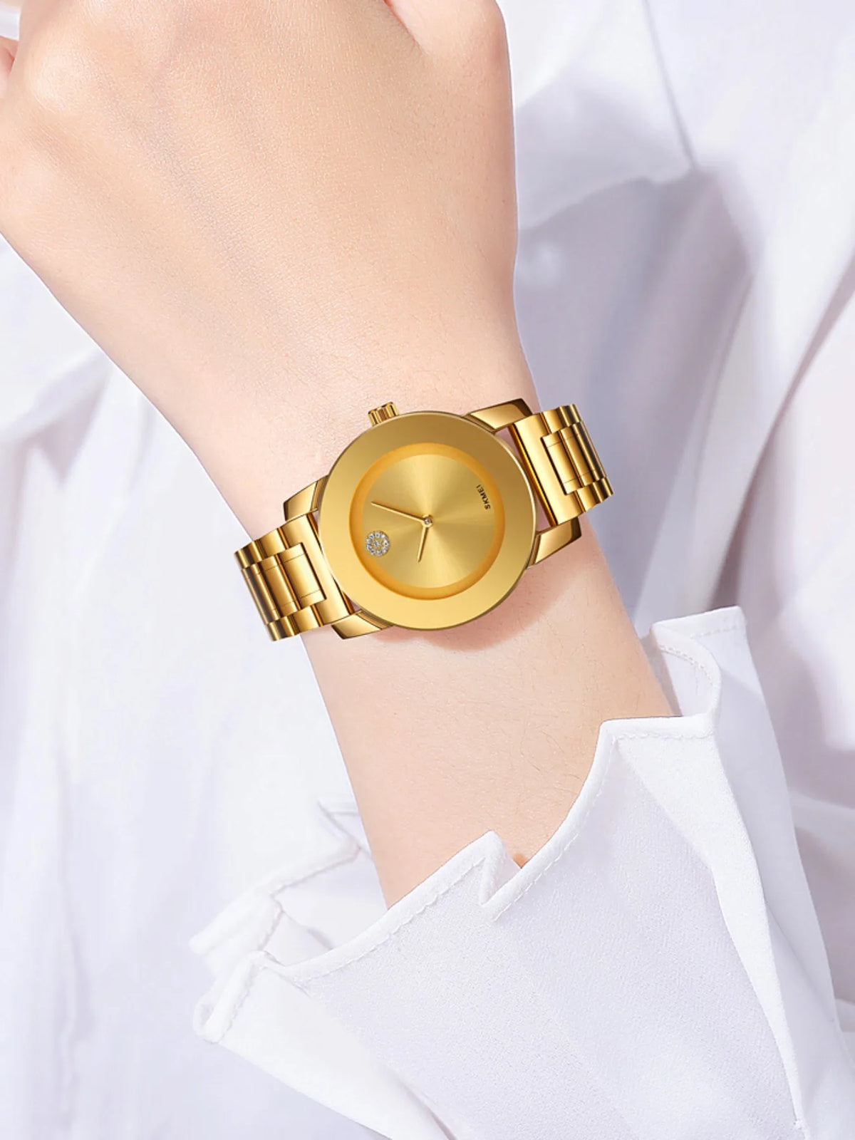 Primer plano de un reloj de cuarzo dorado con caja redonda y eslabones dorados, usado en la muñeca.