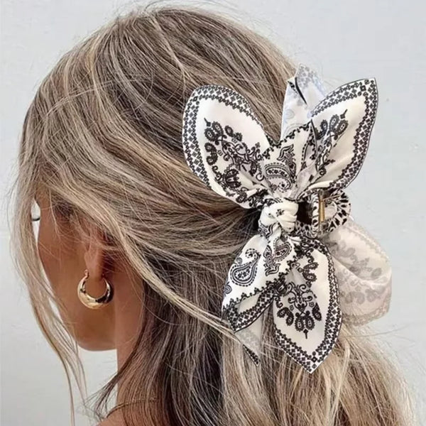 Elegant vintage cashew pattern hair clip tied in a bow worn in a swept-back hairstyle.