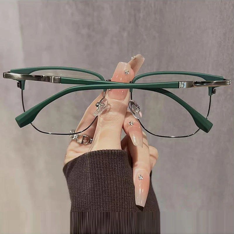 Eine Hand hält eine grüne Anti-Blaulicht-Lesebrille vor einem grauen Hintergrund.