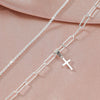 Silver plated CZ anklet chain and cross pendant displayed on a pink fabric background