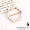 A gold-toned button clip featuring a string of small white pearls on a white background.