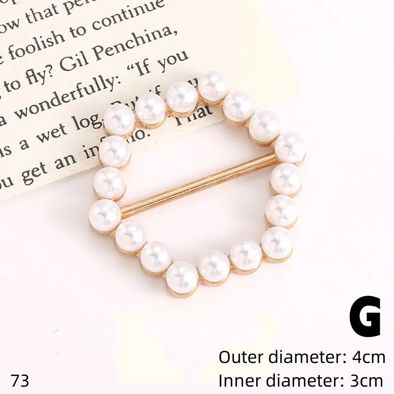 A gold-toned button clip featuring a string of small white pearls on a white background.