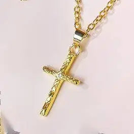 Pendentif de couleur or avec un motif de lettre et de croix.