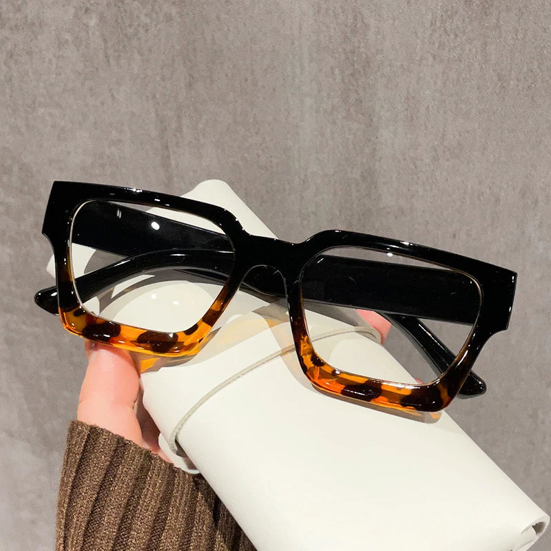 A pair of black square anti-blue light computer glasses resting on a white surface.
