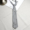 A gray tie featuring a silver star pendant attached by a chain, displayed on a light fabric.
