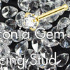 A close-up of cubic zirconia gems used as nose piercing studs, featuring a crystal and gold finish.