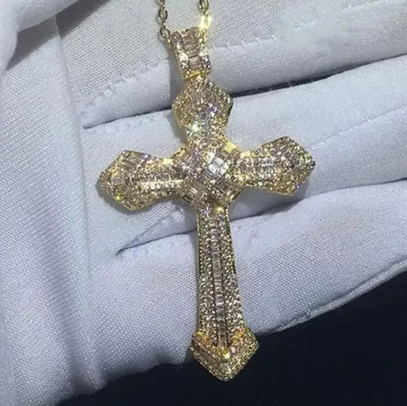 A gold-toned retro Christian cross amulet necklace is displayed on a white glove.