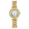 A gold-toned wristwatch featuring a white face, Roman numerals, and surrounding rhinestone detailing.
